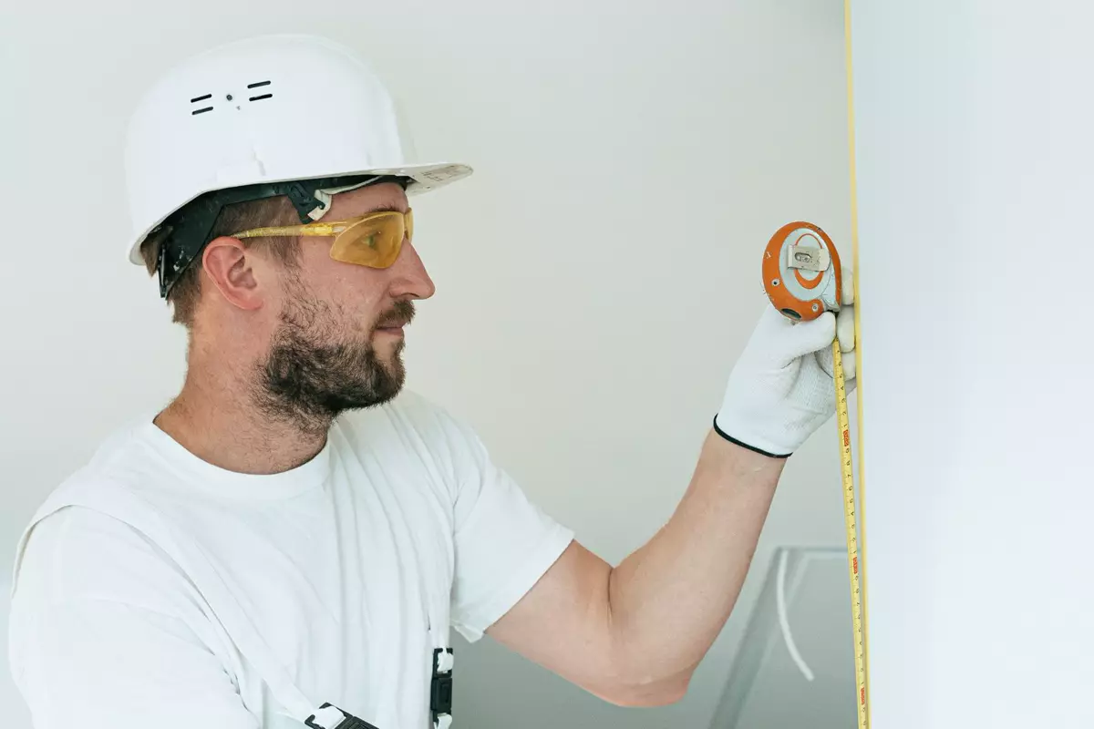 Handwerker misst eine Wand mit dem Maßband für ein genaues Küchenaufmaß